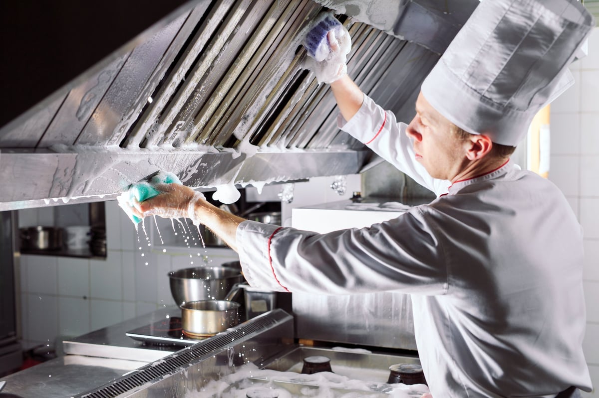 Restaurant kitchen exhaust hood being cleaned - professional hood cleaning service