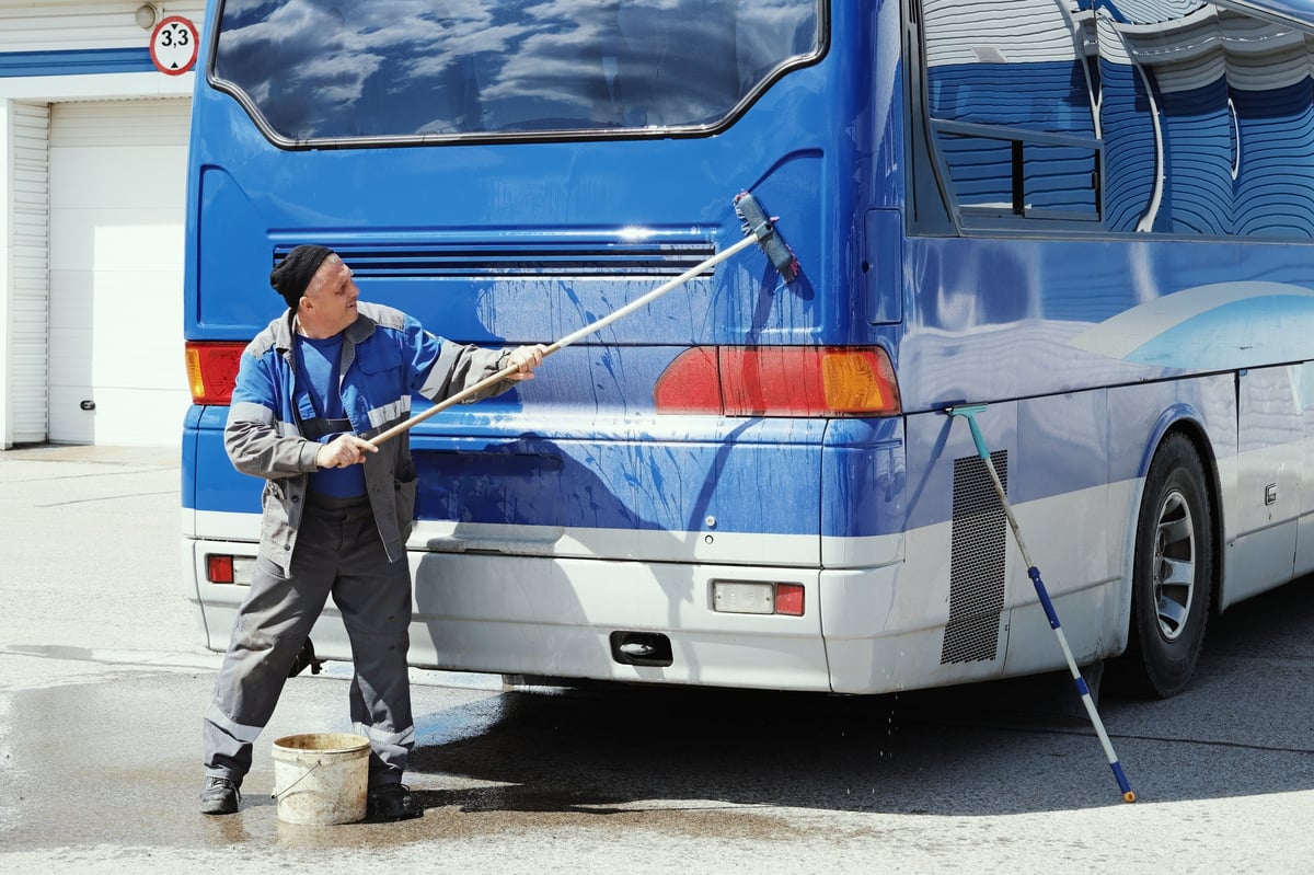Worker cleaning transit bus exterior