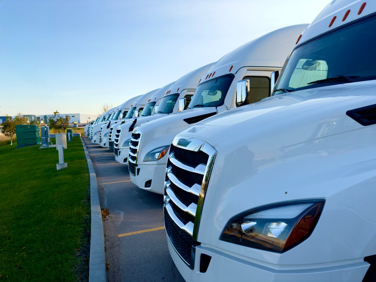Several white commercial trucks parked in a row in a lot
