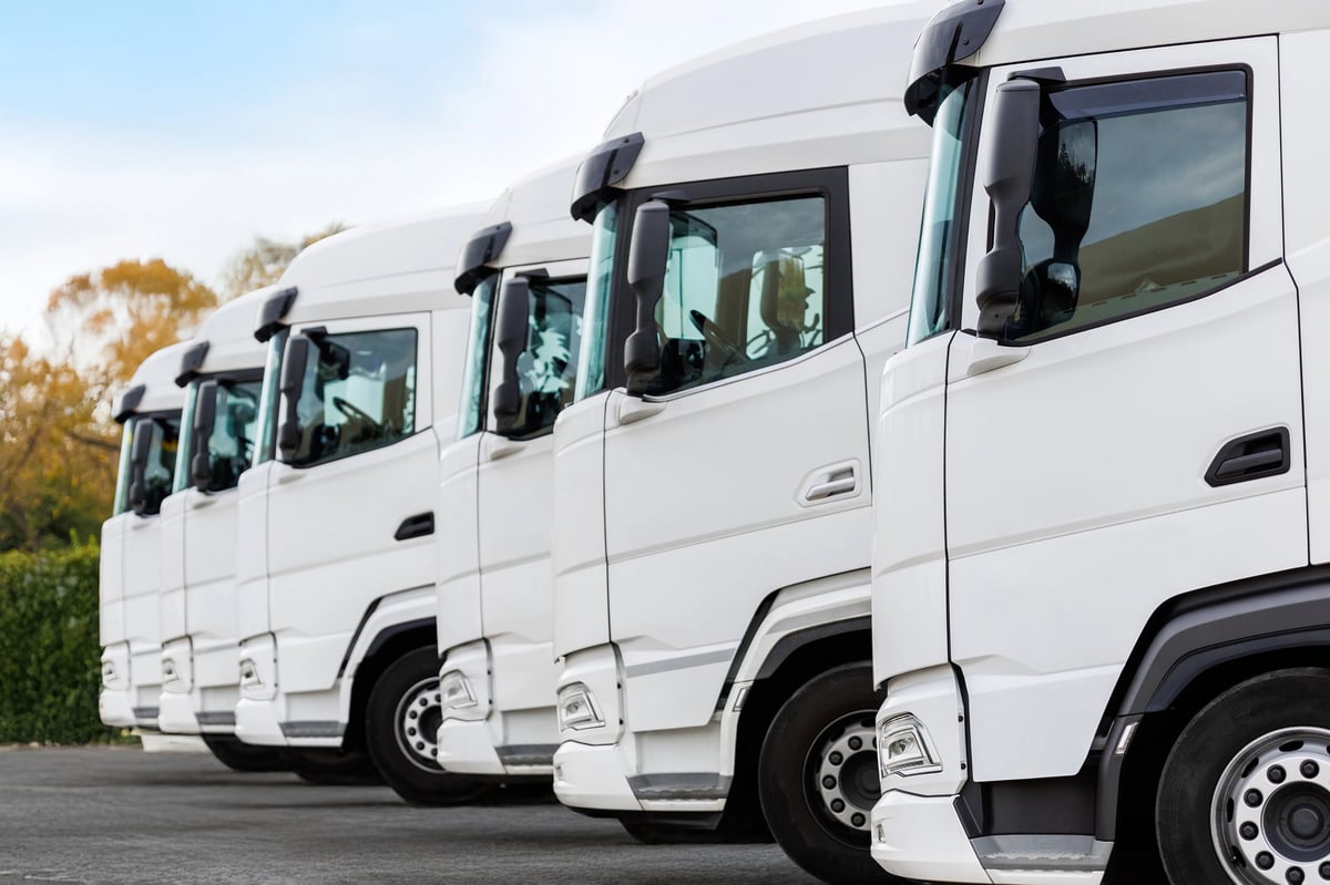 Line of commercial trucks parked in a row at a fleet yard