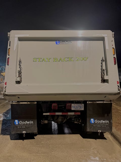 Rear view of Godwin dump truck with white bed displaying STAY BACK 200 feet warning text